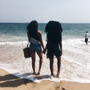 two black girls at the beach, yellow sand and blue water